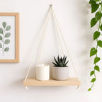 Prateleira suspensa com planta e vela em parede clara

