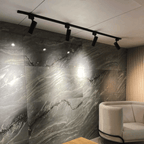 Trilho preto instalado com 4 spots iluminando parede texturizada

