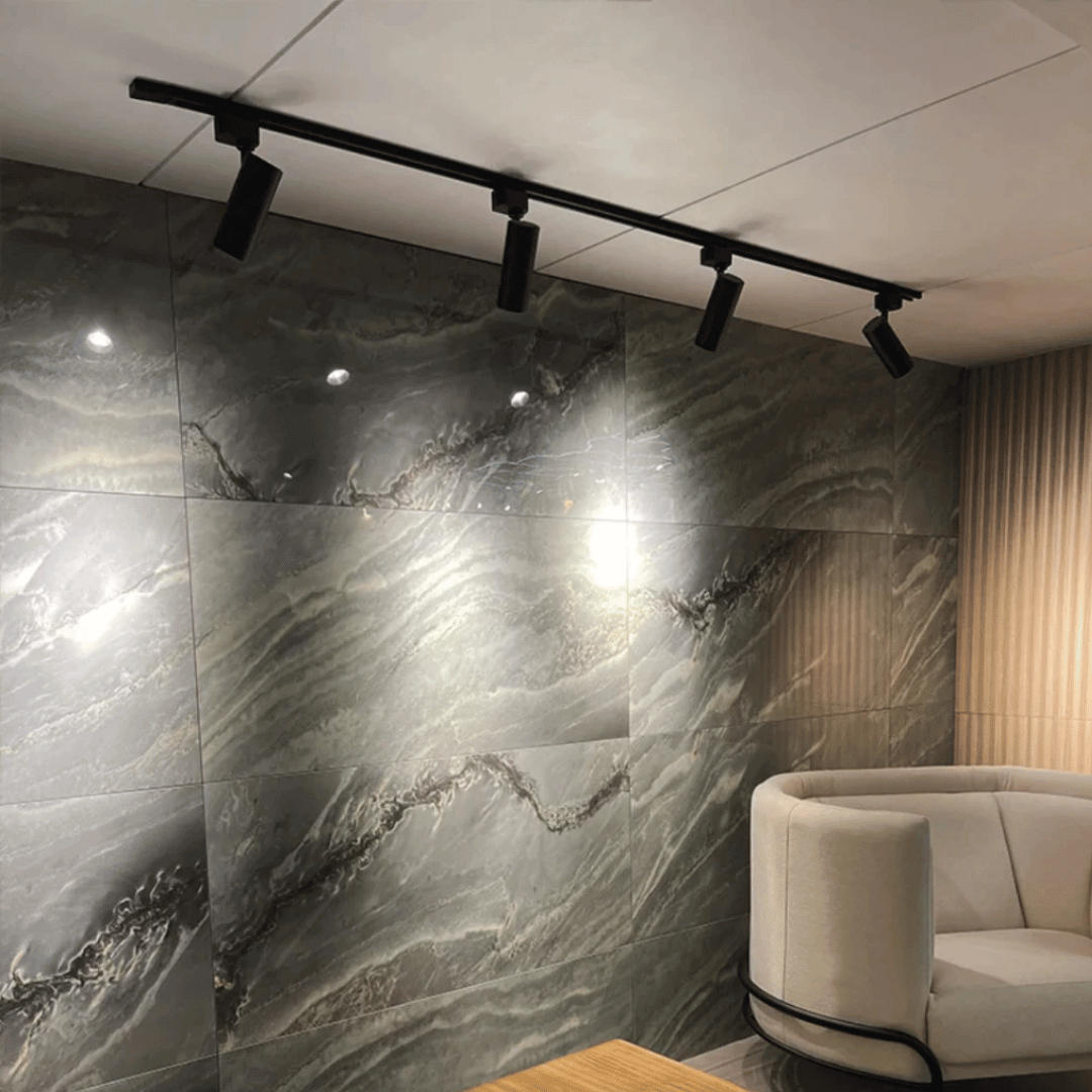 Trilho preto instalado com 4 spots iluminando parede texturizada

