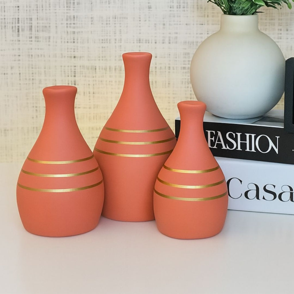 Vasos decorativos terracota com detalhe dourado em ambiente clean

