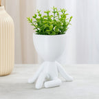 Mood Pernas Cruzadas com flor artificial sobre mesa clara.

