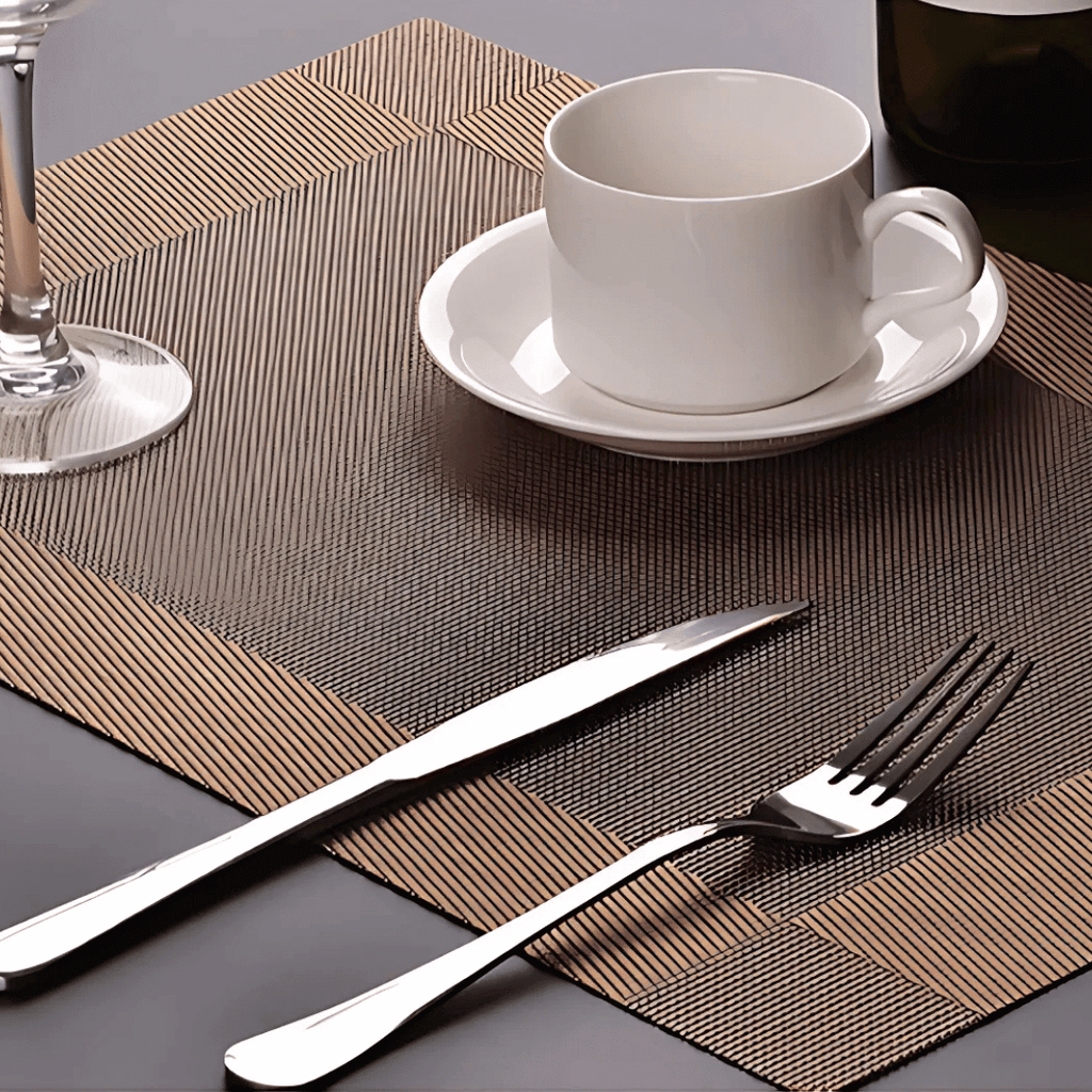 Detalhe de jogo americano com xícara branca e talheres brilhantes

