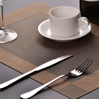 Detalhe de jogo americano com xícara branca e talheres brilhantes

