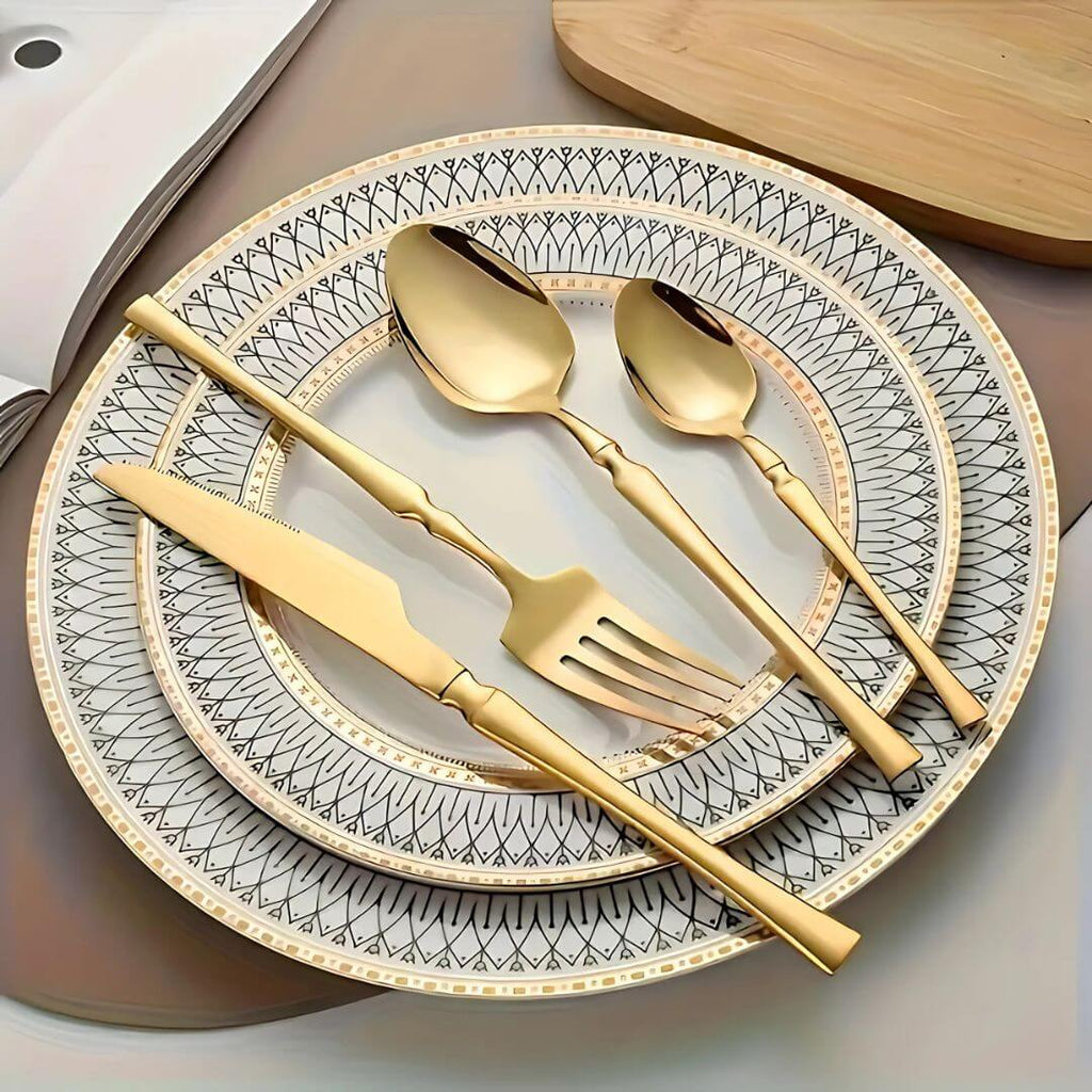 Talheres dourados dispostos sobre louça decorada em mesa elegante

