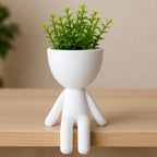 Mood Sentado (pernas soltas) em prateleira de madeira clara.

