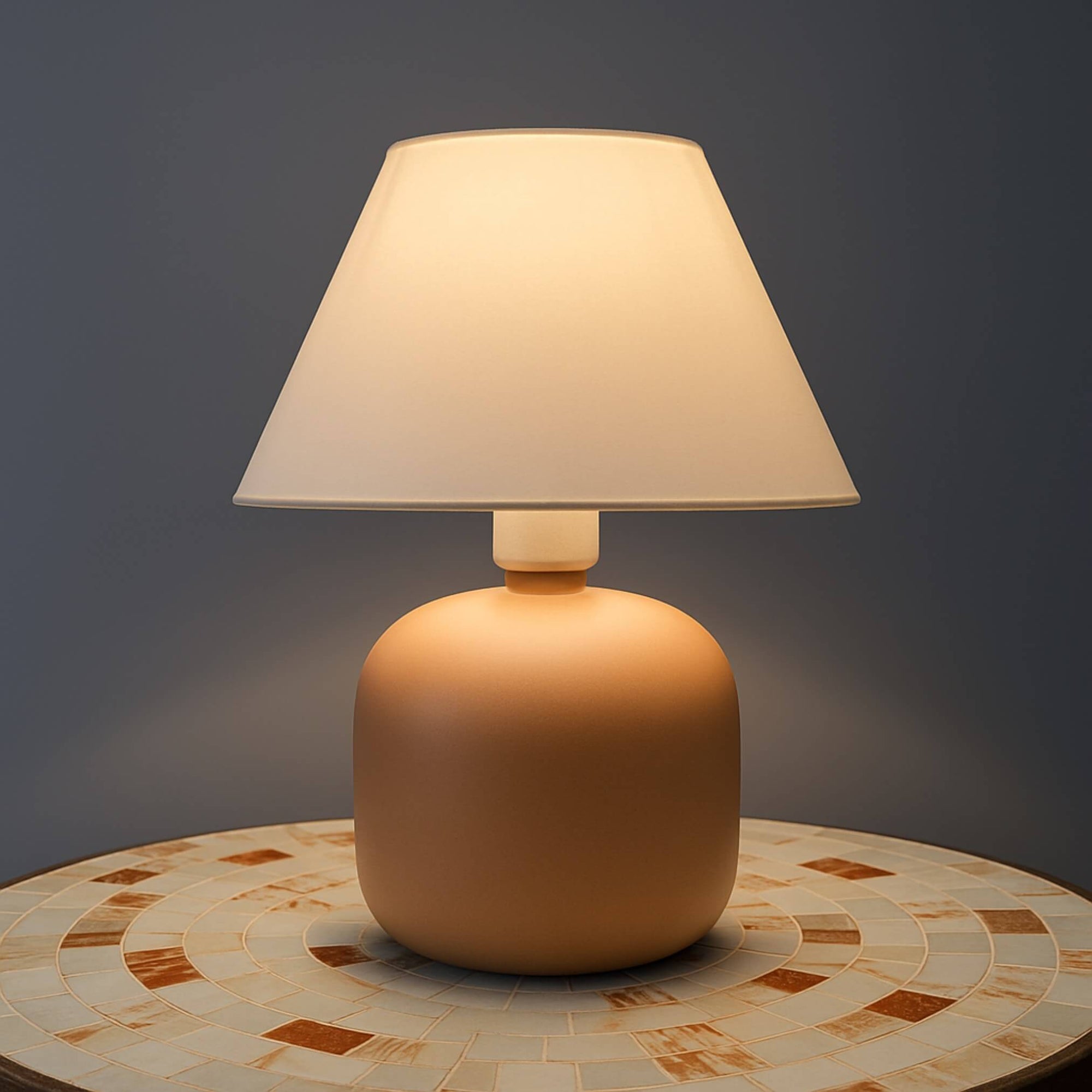 Abajur compacto sobre mesa ao lado de plantas e livros

